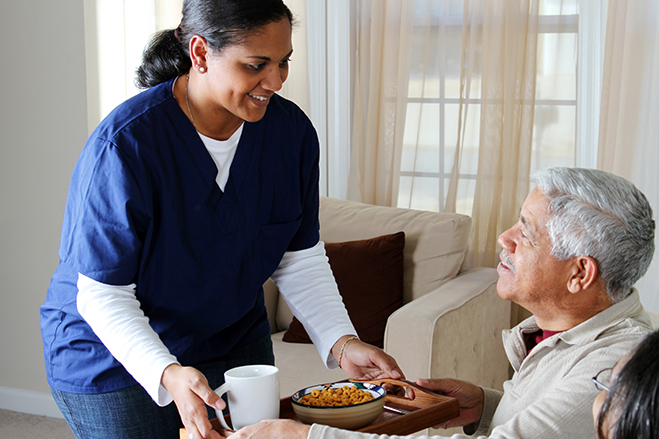 a nurse serving a man a breakfast